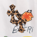 White pants featuring a large leopard-print cross appliqué with orange accent
