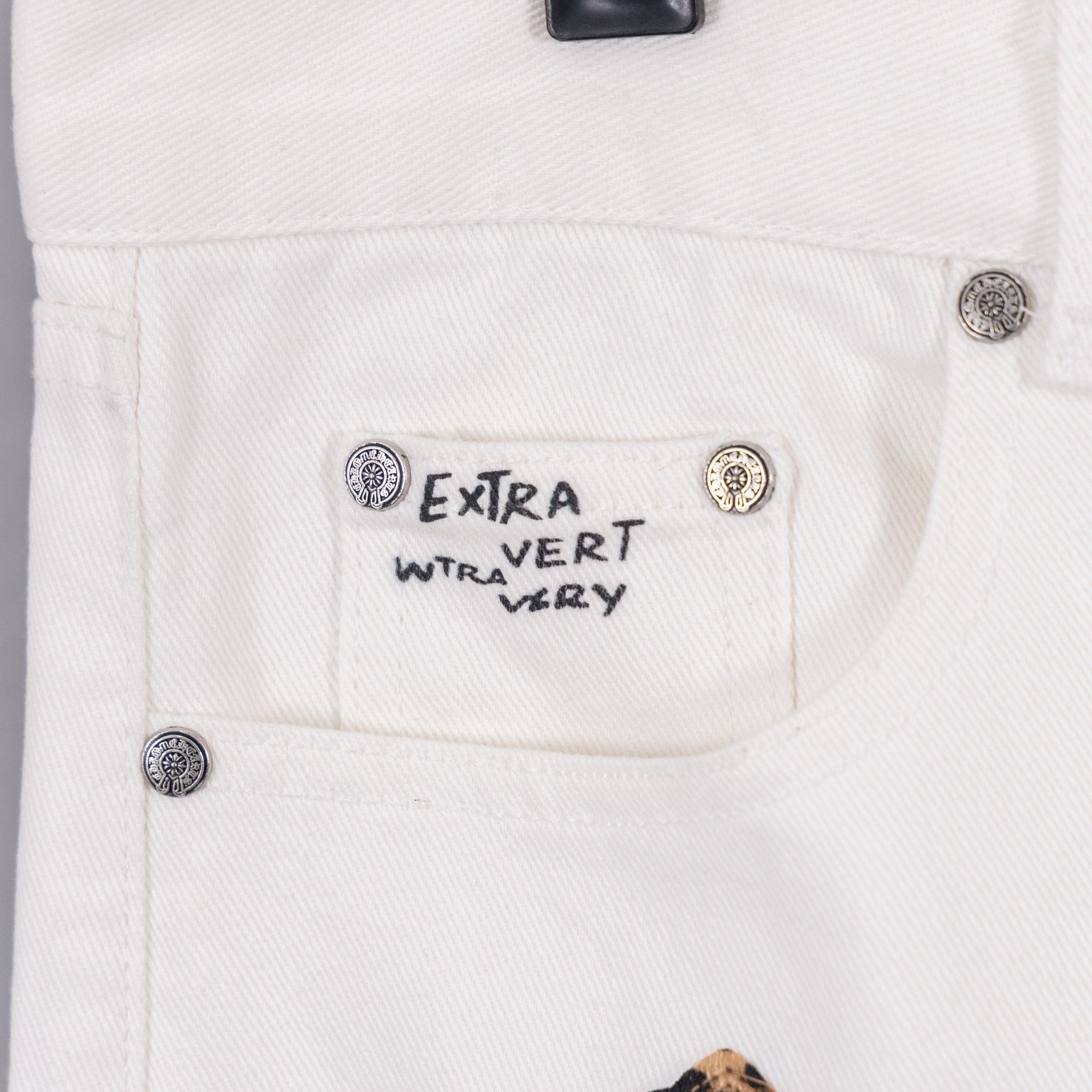 White pants with “Extra Vert Very” label and round button details