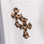 White pants with medium leopard-print cross appliqué centered on the leg