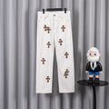 White denim pants with small leopard-print cross patches on the front legs