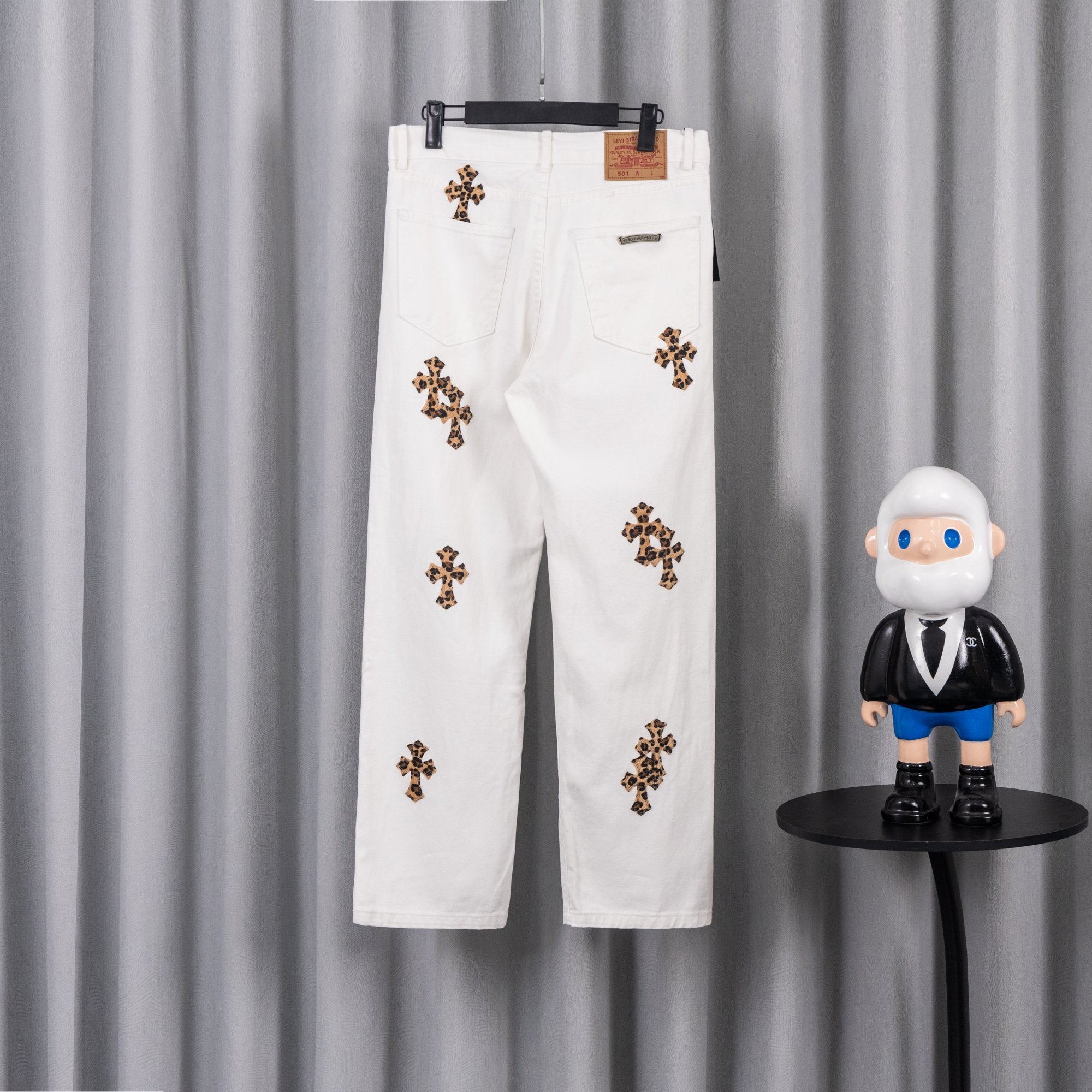 White denim pants with leopard-print cross patches and a buttoned waistband