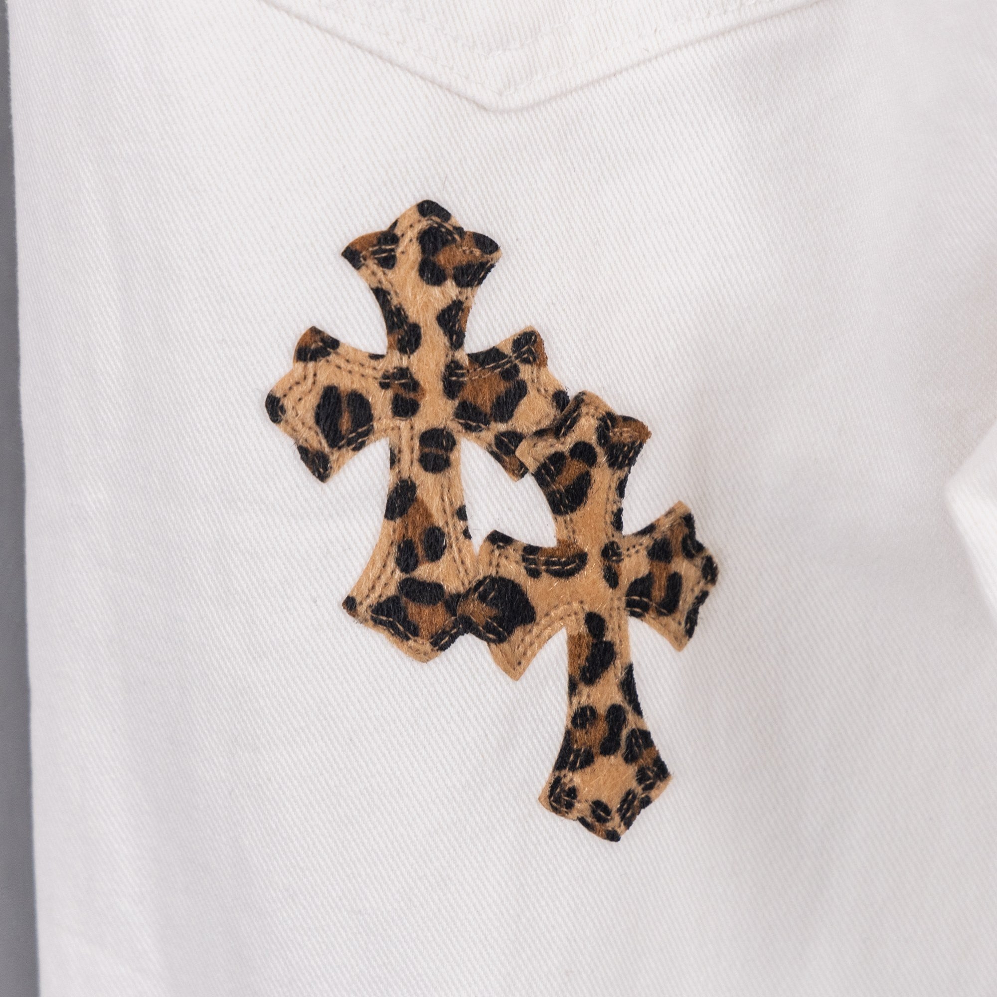 Leopard-print cross patch on white denim pants