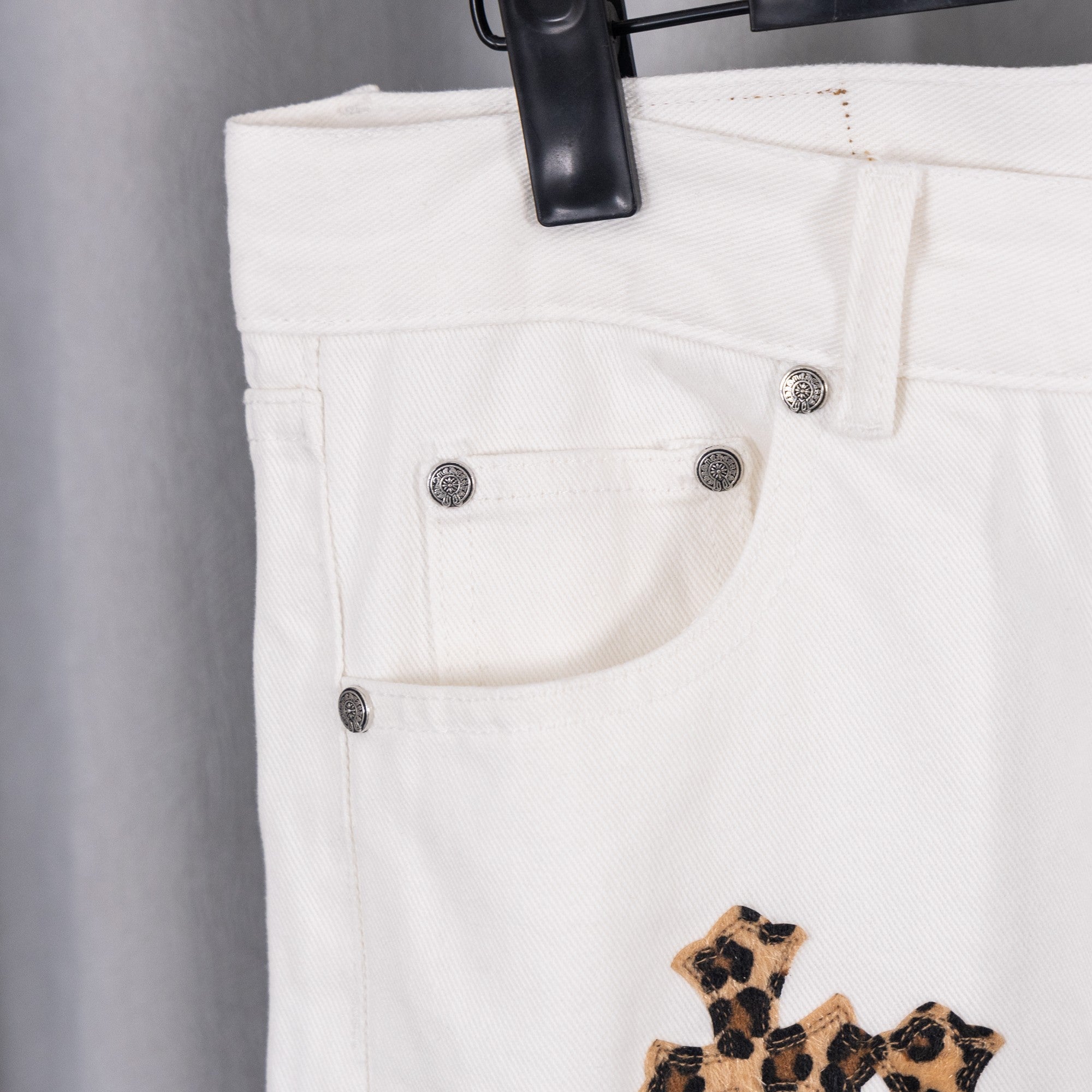 White pants with button fly and waistband cross appliqué