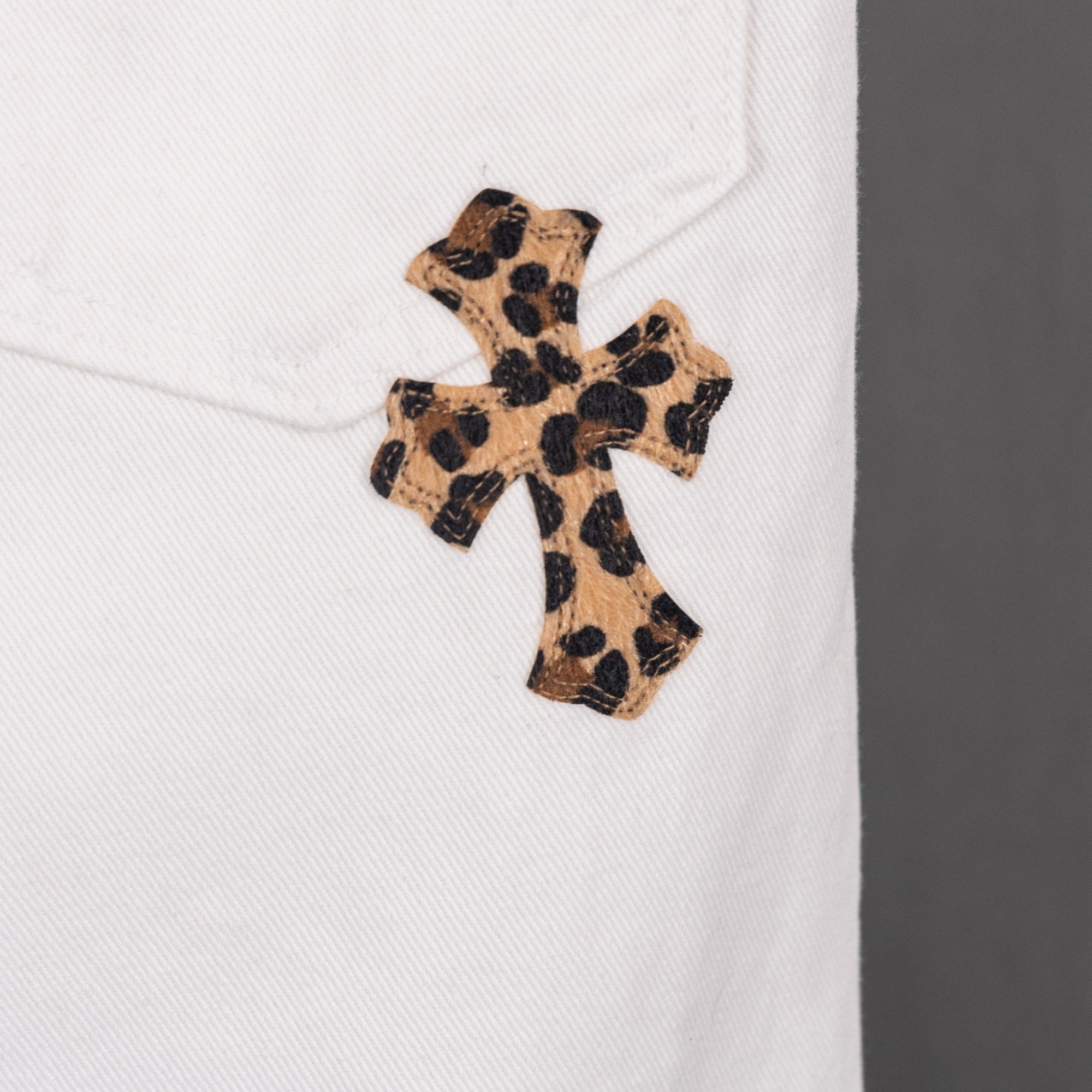 White pants with leopard-print cross appliqué on leg