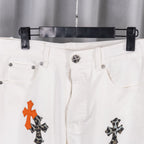 White denim pants waistband with button and orange/black cross design on leg