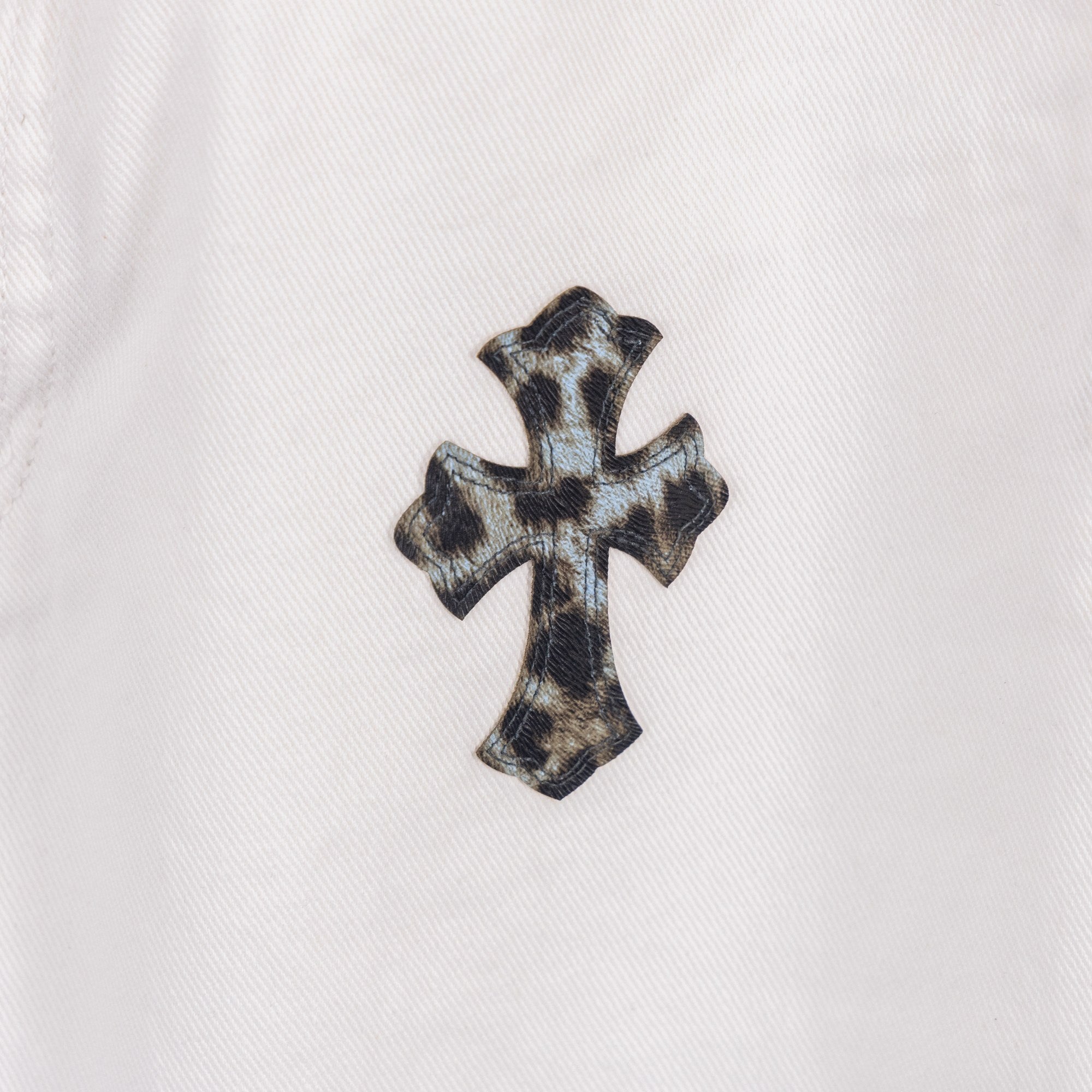 Orange and black cross applique on white denim pants