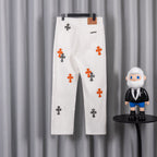 White denim pants with scattered orange and black cross print, belt loops