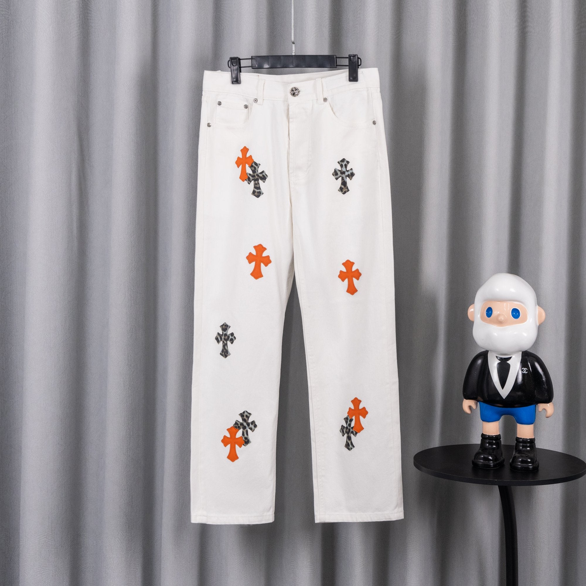 White denim pants with orange and black cross print, button-and-zip closure