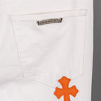 White denim pants pocket with small logo patch and orange cross applique