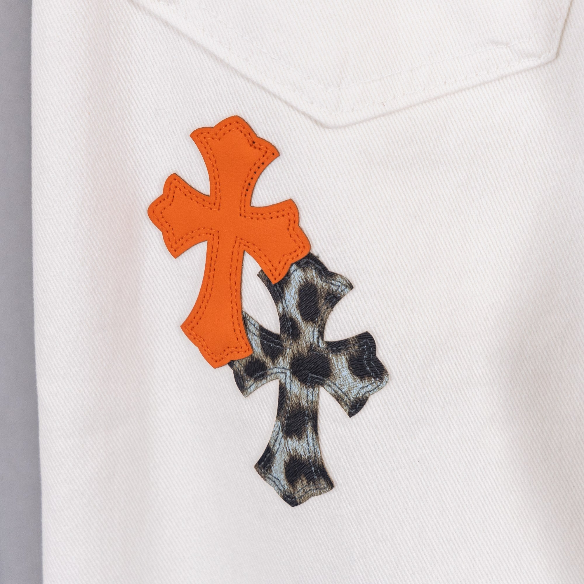Orange and black cross applique on white denim pants