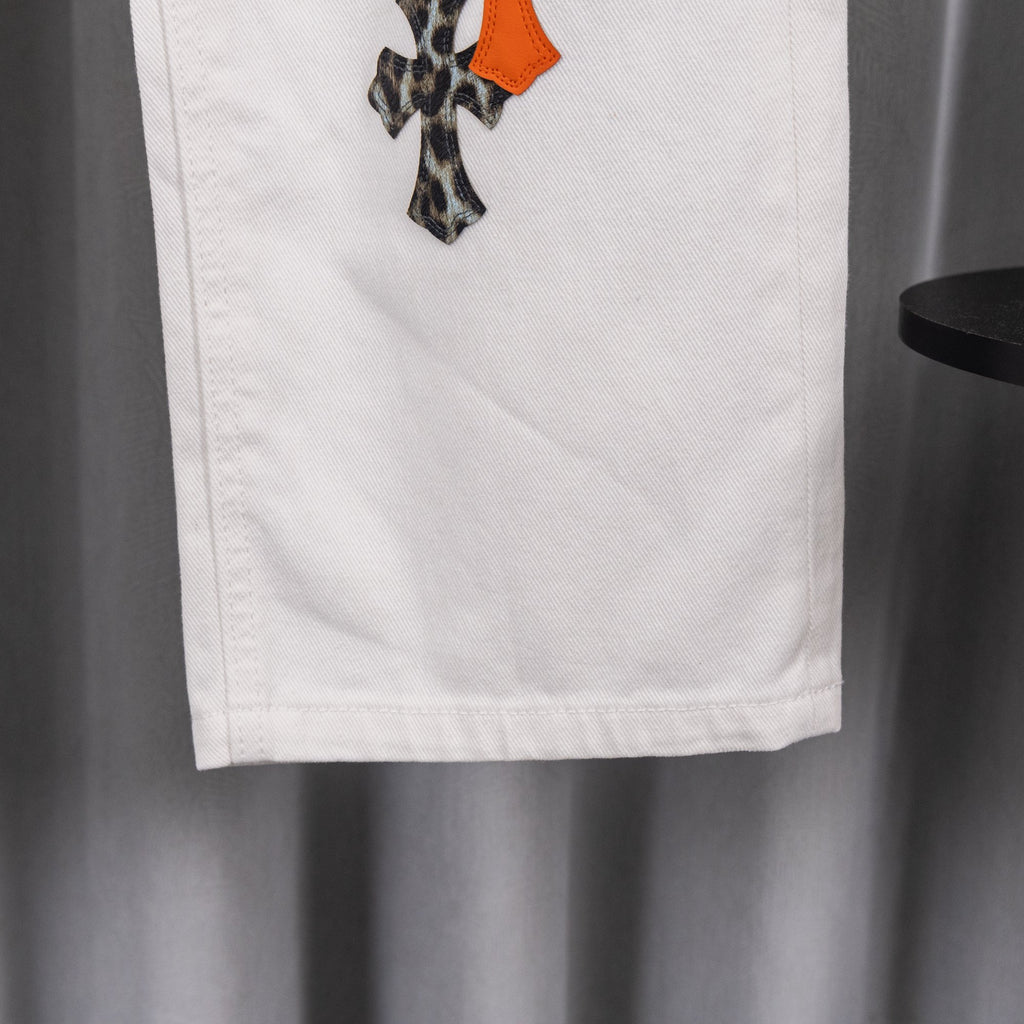 White chrome pants with side pocket and small orange appliqué accent