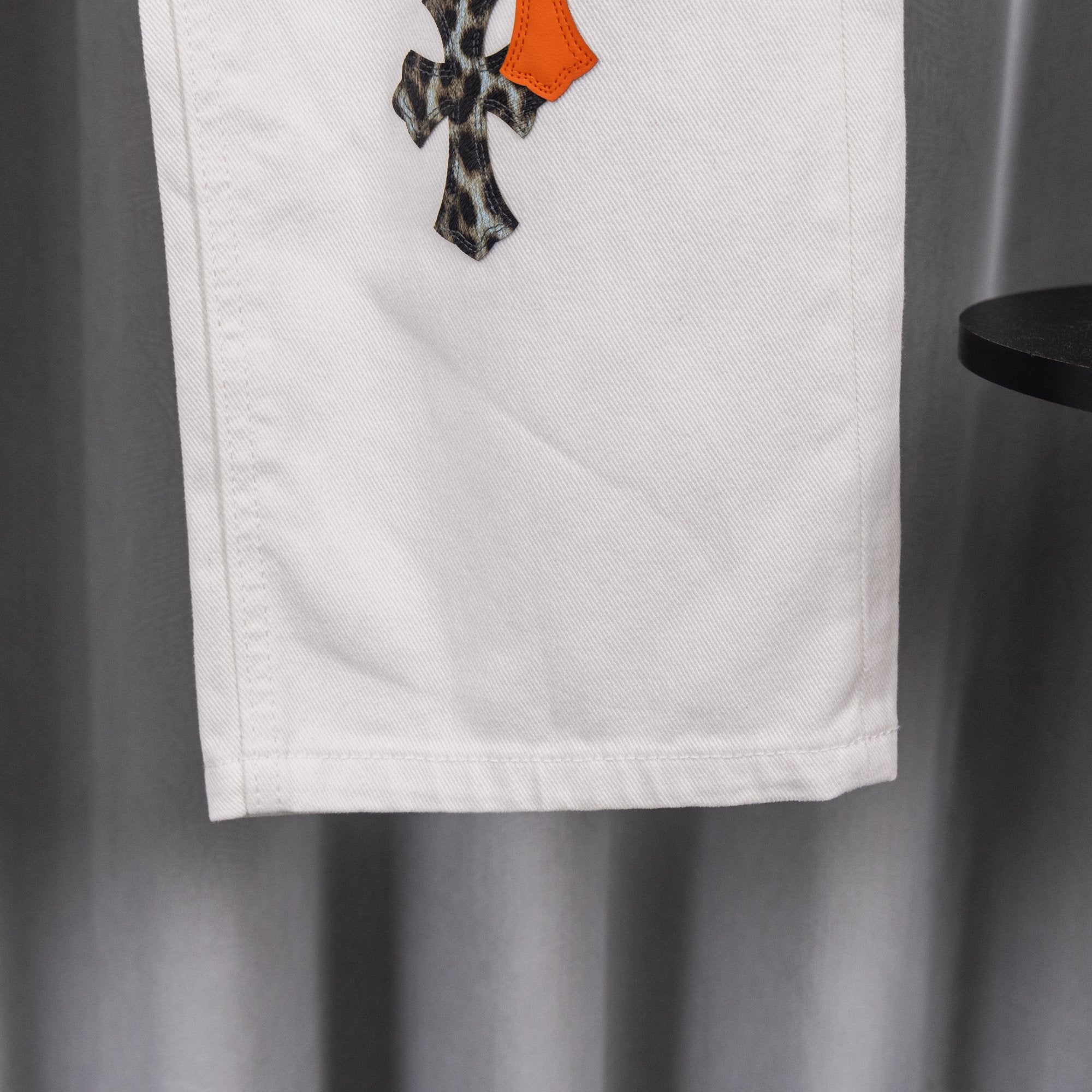 White chrome pants with side pocket and small orange appliqué accent