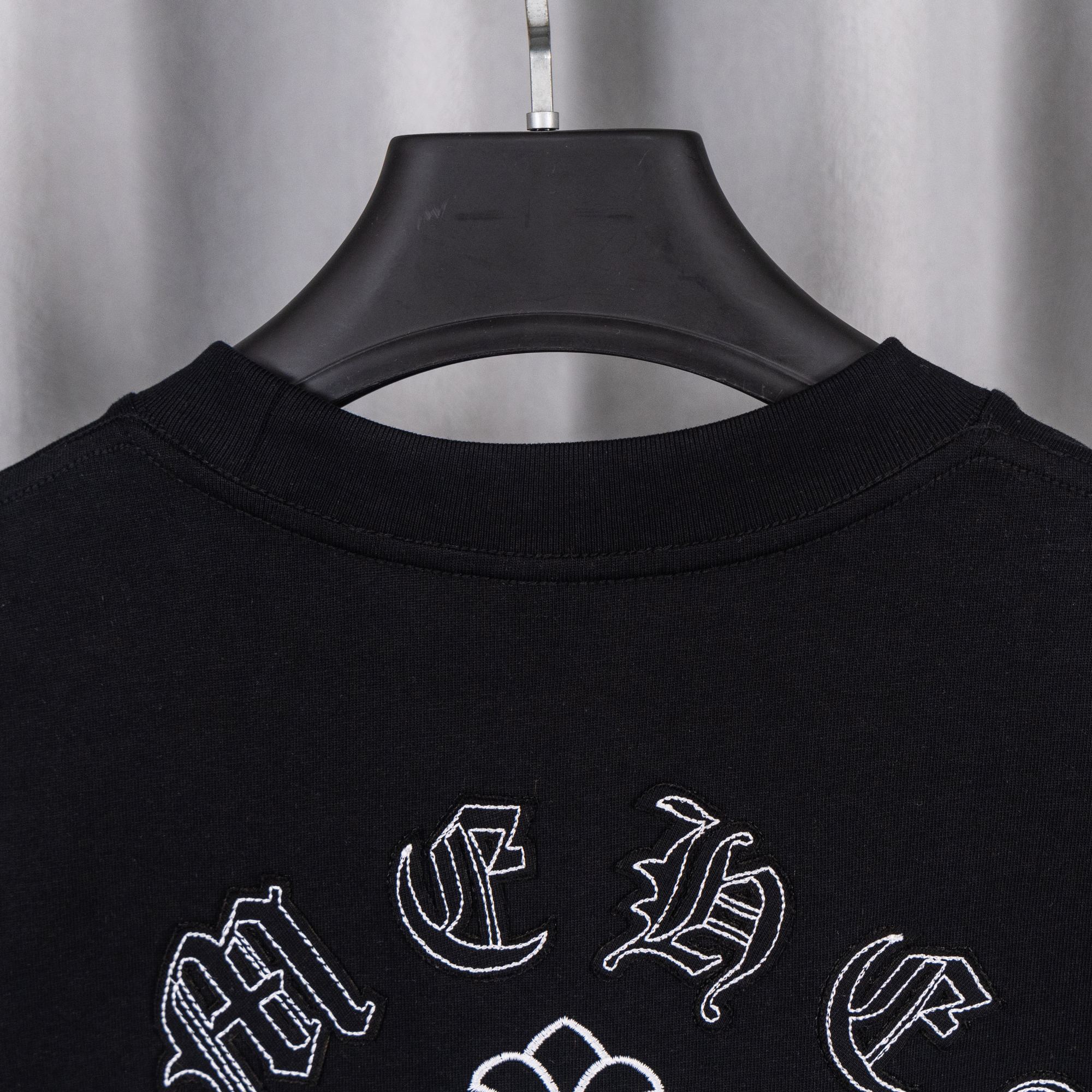 Black crew-neck T-shirt with partial neckline and scattered white cross emblems