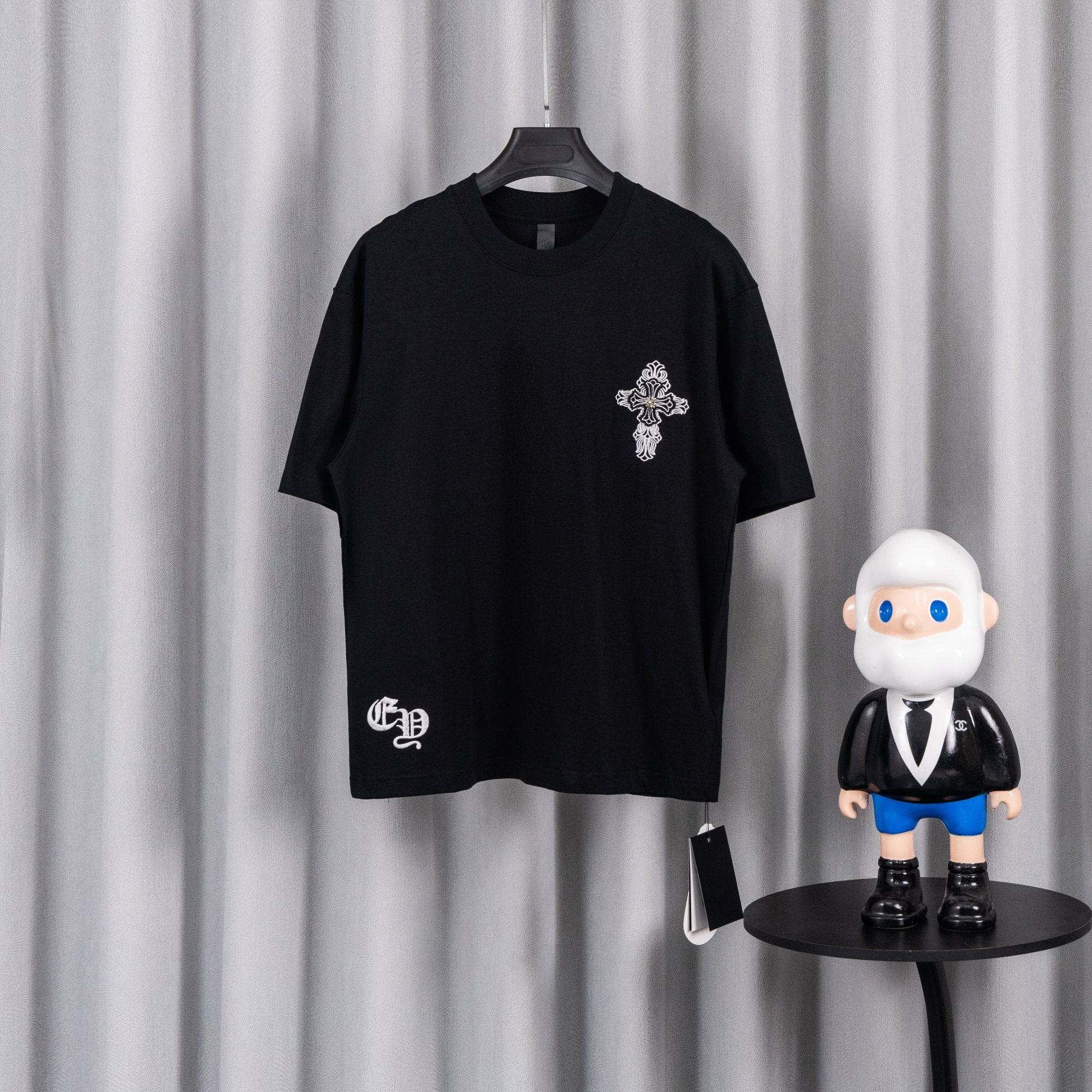 Black short-sleeve graphic T-shirt with small cross emblem on the chest