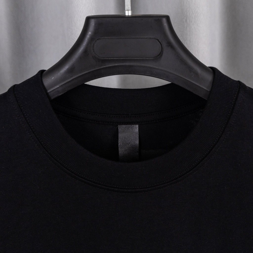 Black crew-neck T-shirt with close-up of ribbed collar and interior tag
