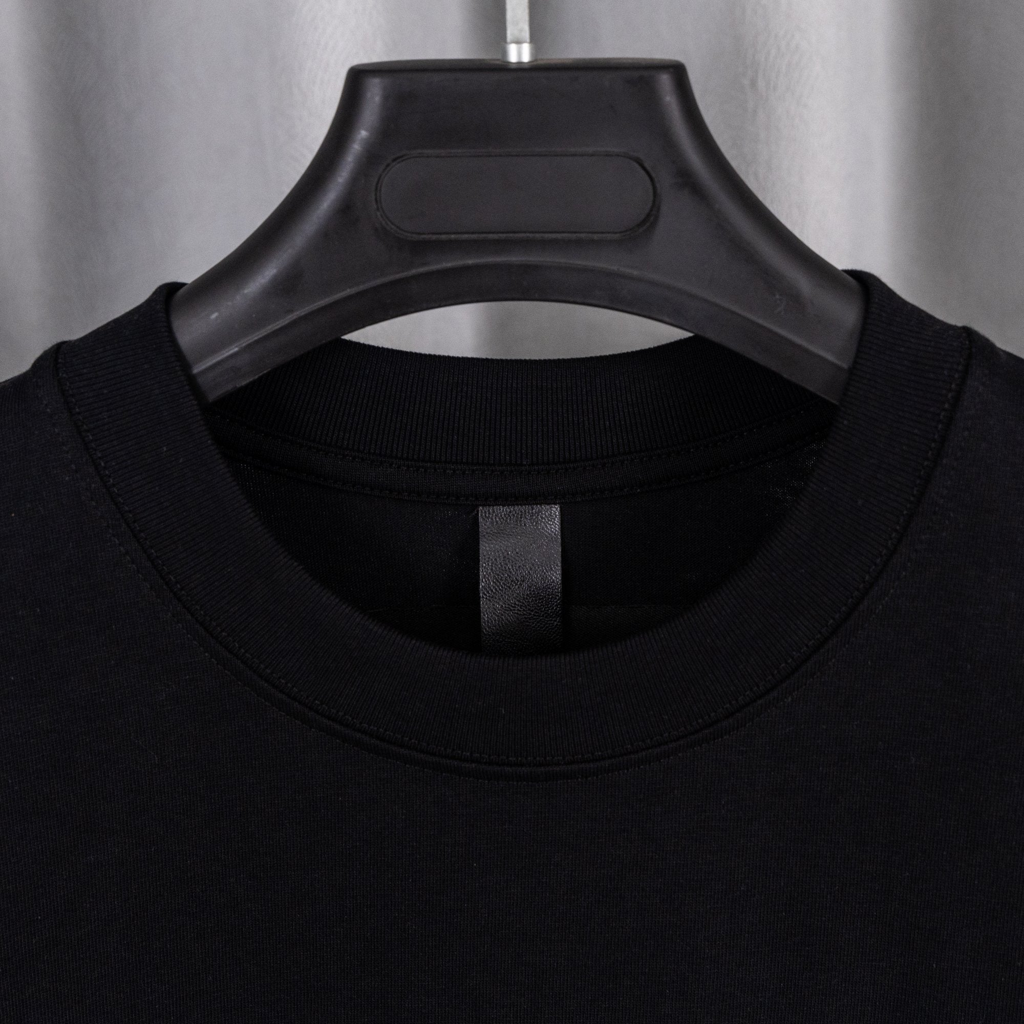 Black crew-neck T-shirt with close-up of ribbed collar and interior tag