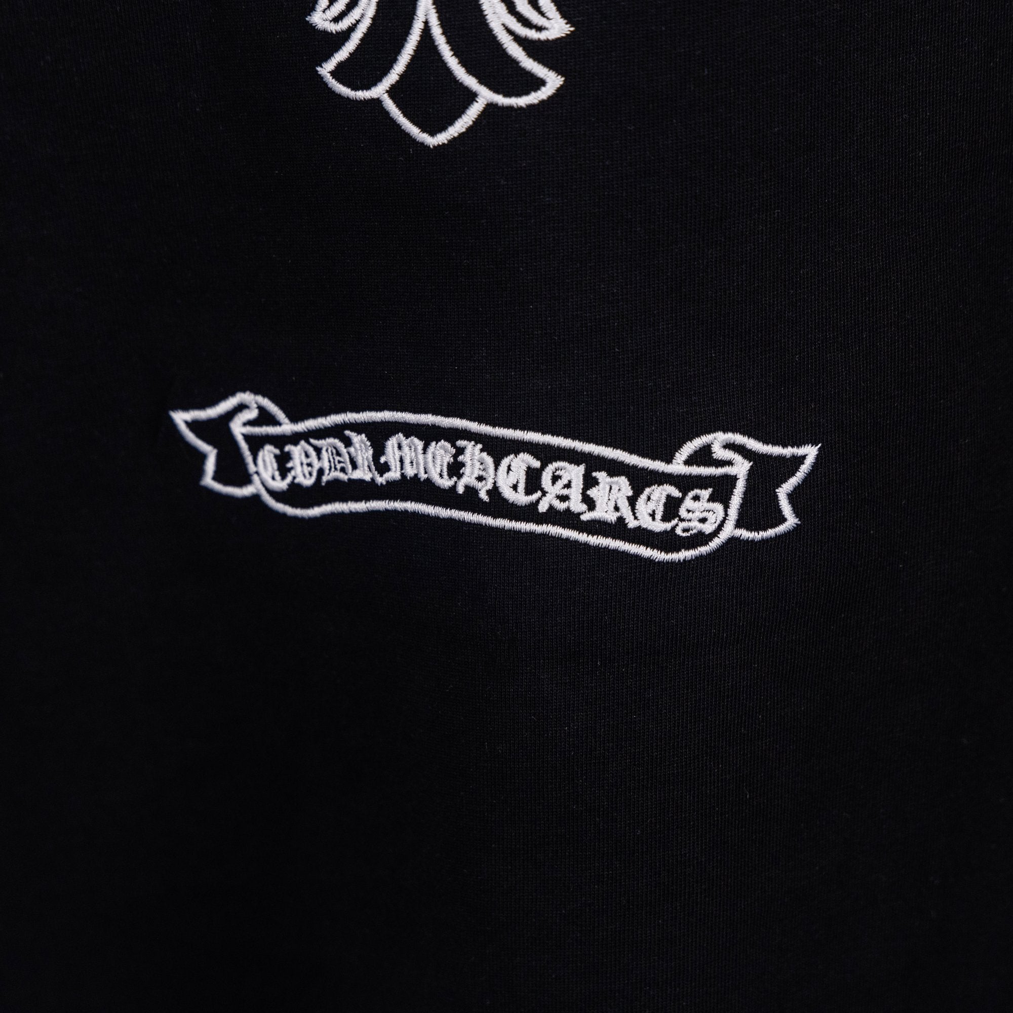 Black T-shirt with embroidered white ribbon logo text under the cross graphic