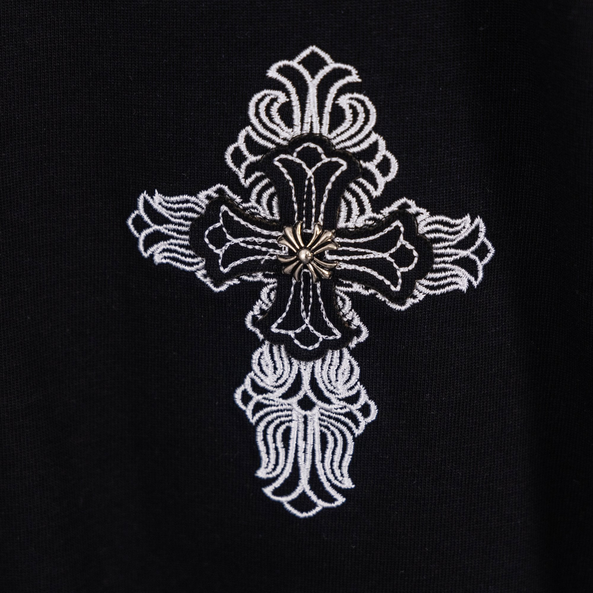 Black T-shirt with detailed white cross emblem featuring a small center gem