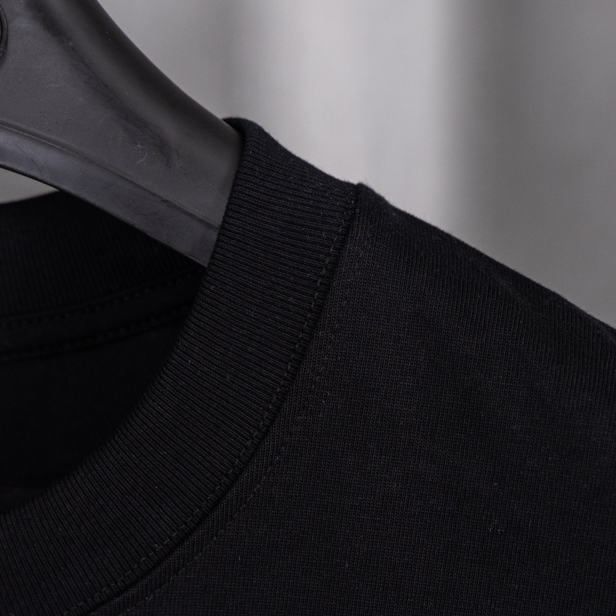 Black crew-neck top with ribbed collar and stitching
