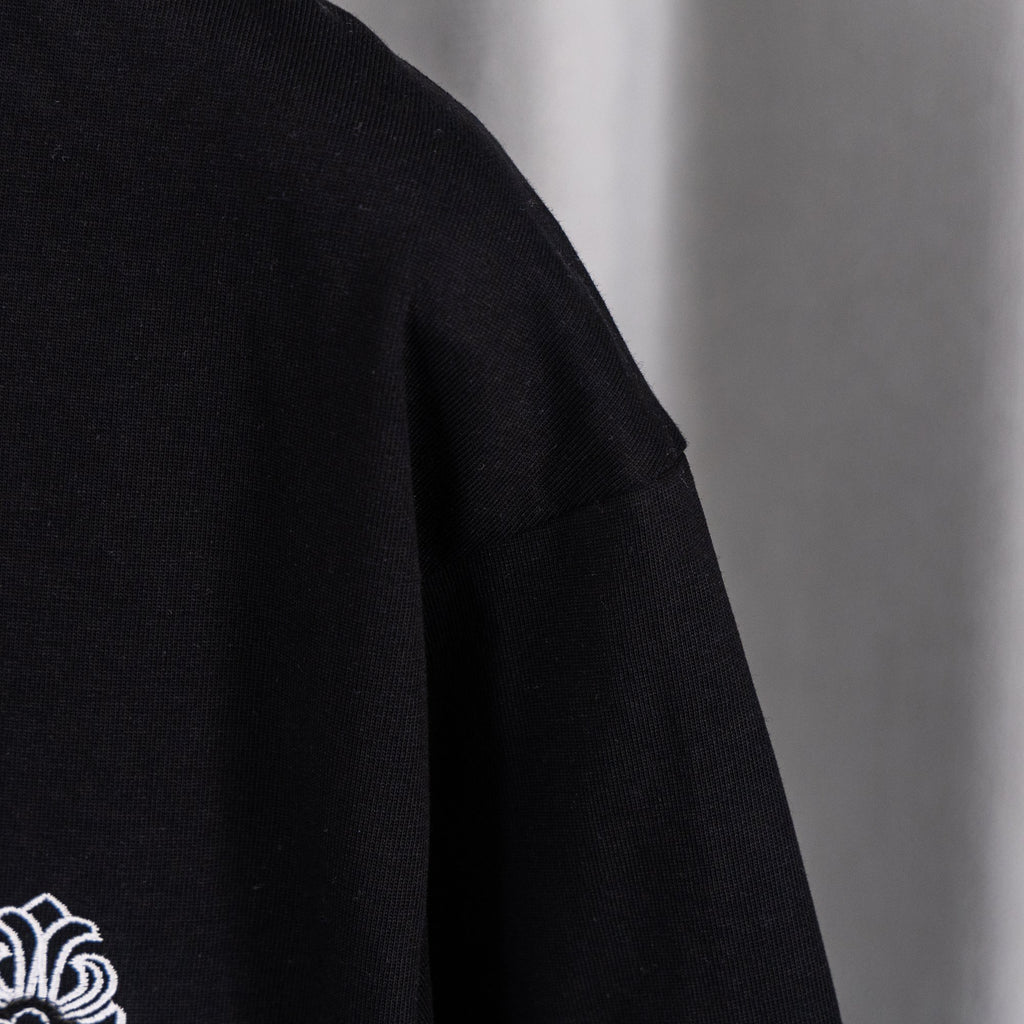 Black crew-neck top with partial white logo graphic