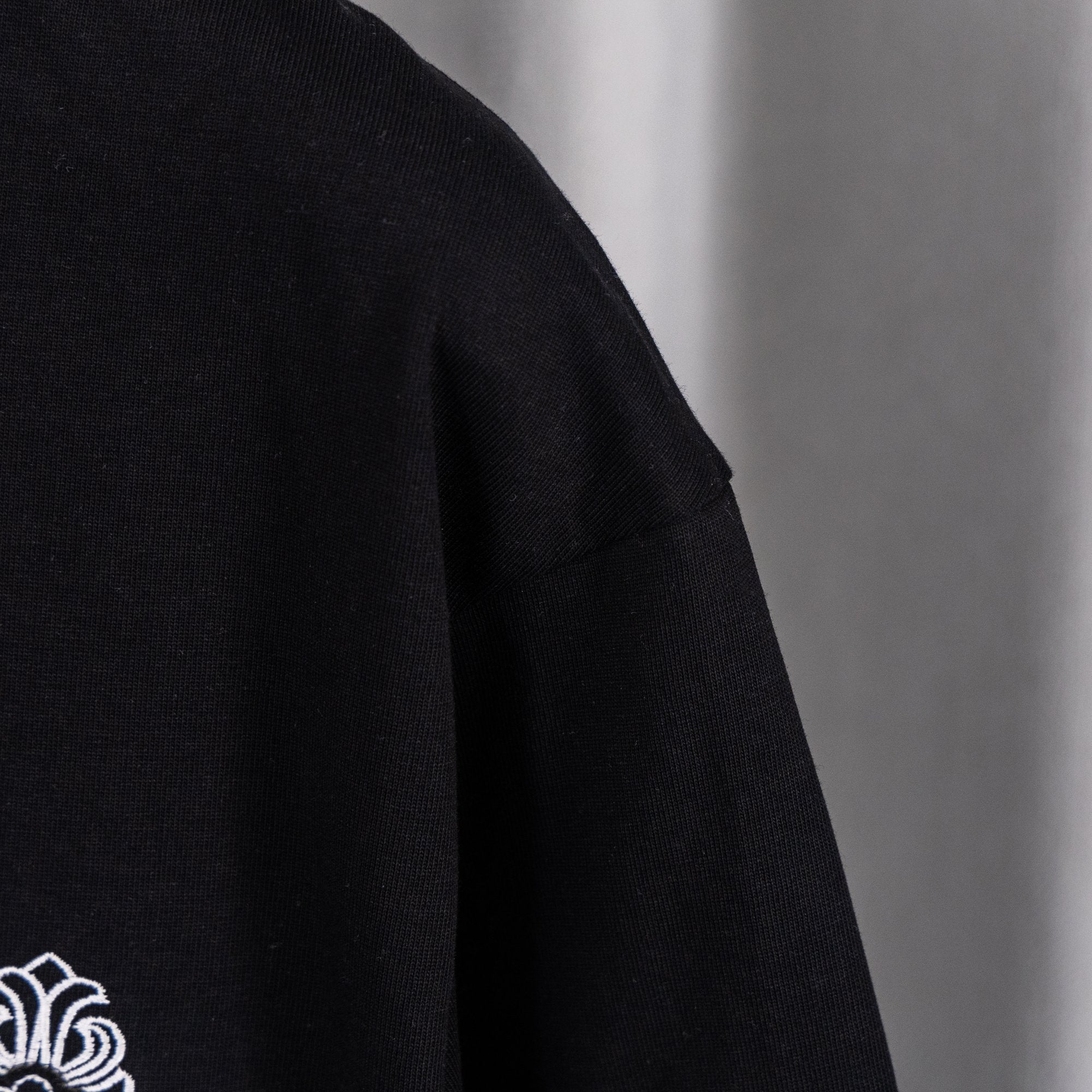 Black crew-neck top with partial white logo graphic