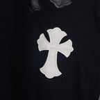 Black T-shirt with white cross applique patch, stitched details.