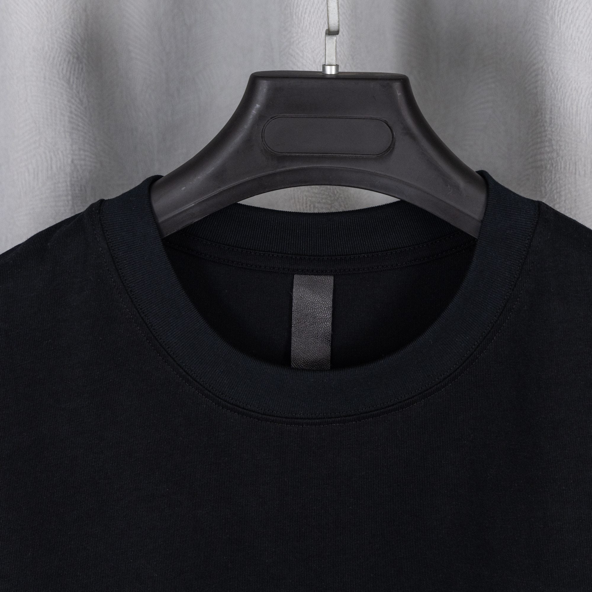 Black crewneck T-shirt neckline with central facing seam.
