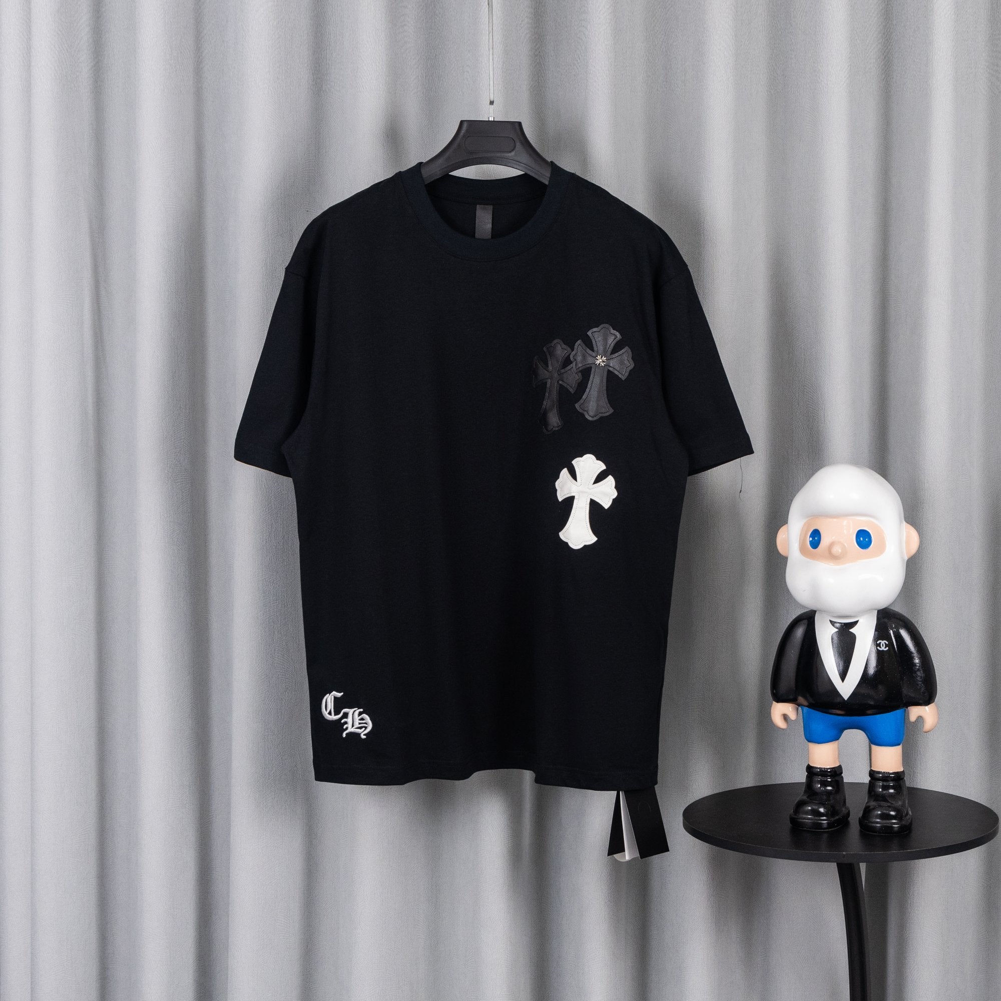 Black short-sleeve T-shirt with white and gray cross chest appliques.