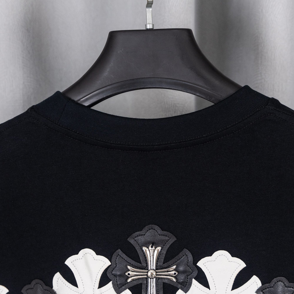 Black T-shirt collar with large cross applique near upper back.