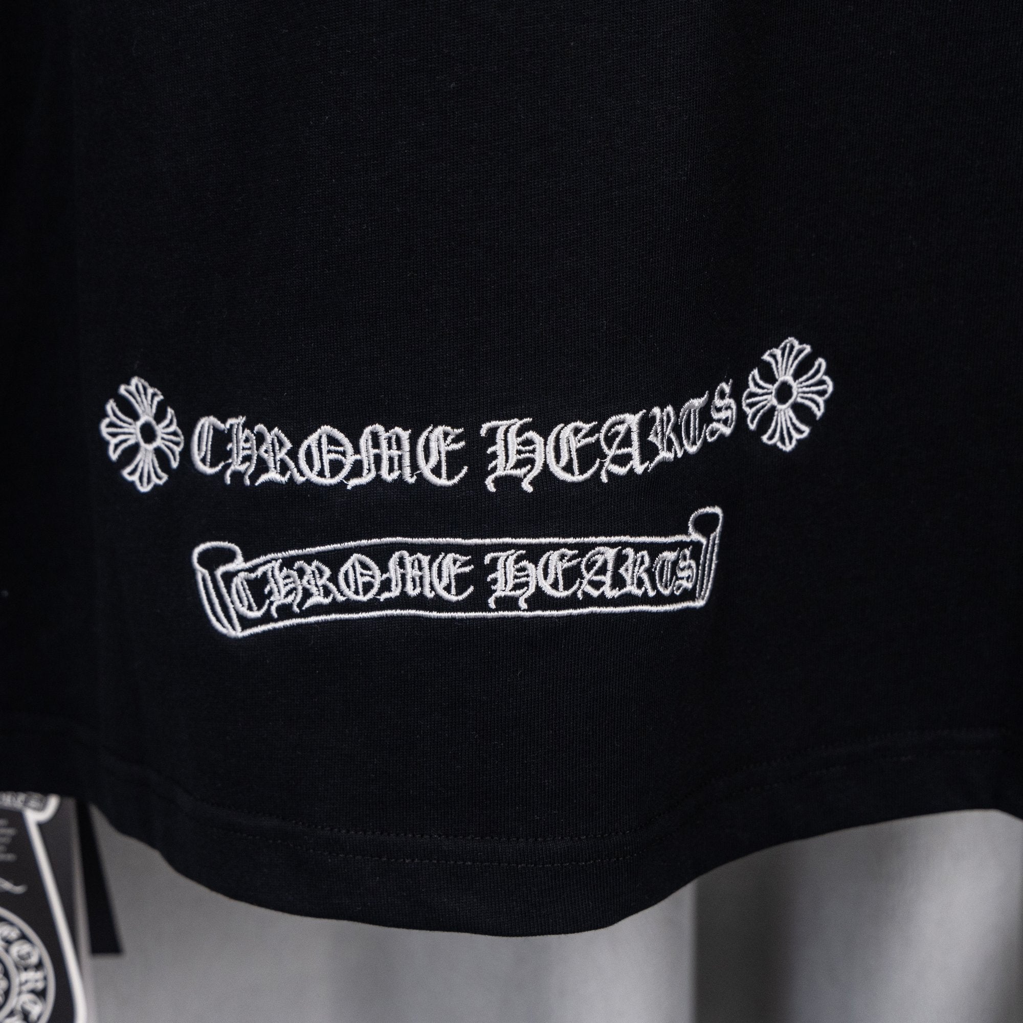 Black short-sleeve shirt with white embroidered emblem and banner text