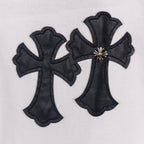 White T-shirt close-up of two black cross appliques with gold accents