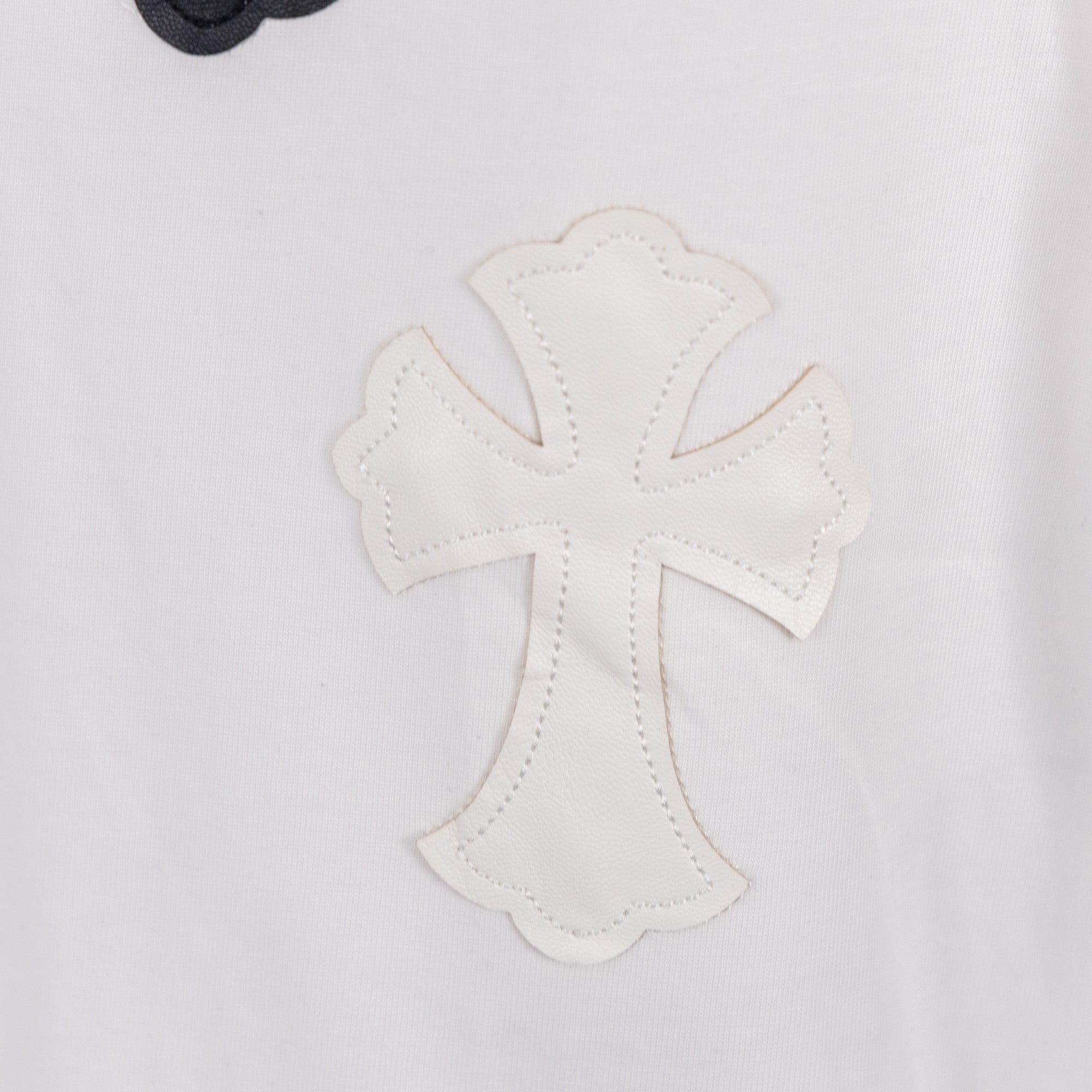 White T-shirt close-up of white-on-white cross applique with stitched outline