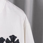 White T-shirt side with small black cross applique on sleeve