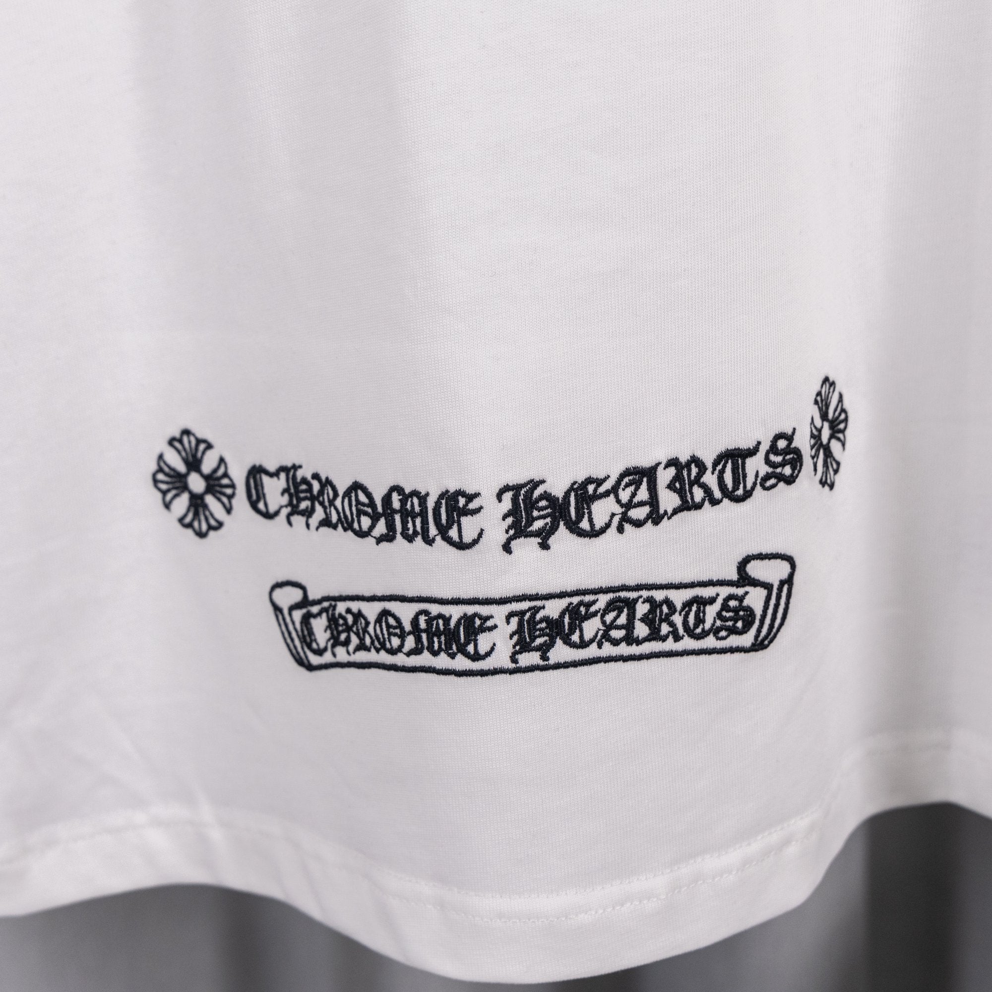 White short-sleeve shirt with 'Chrome Hearts' style logo text