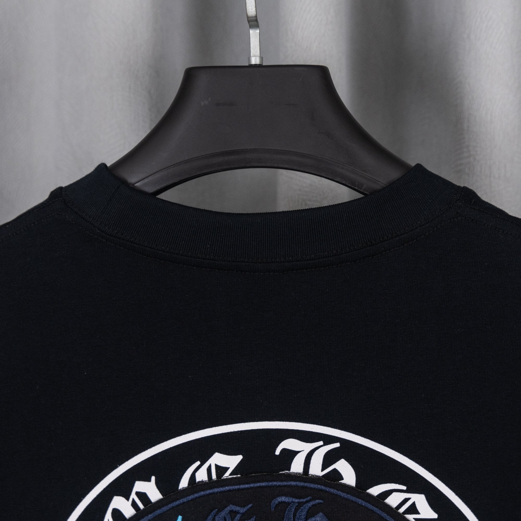 Black T-shirt back upper with partial circular emblem graphic