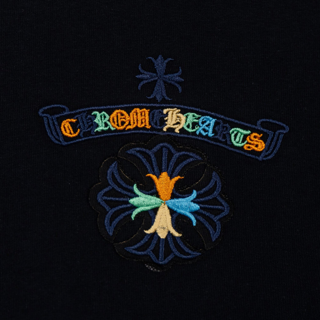 Black T-shirt chest logo detail with colorful ribbon and flower emblem