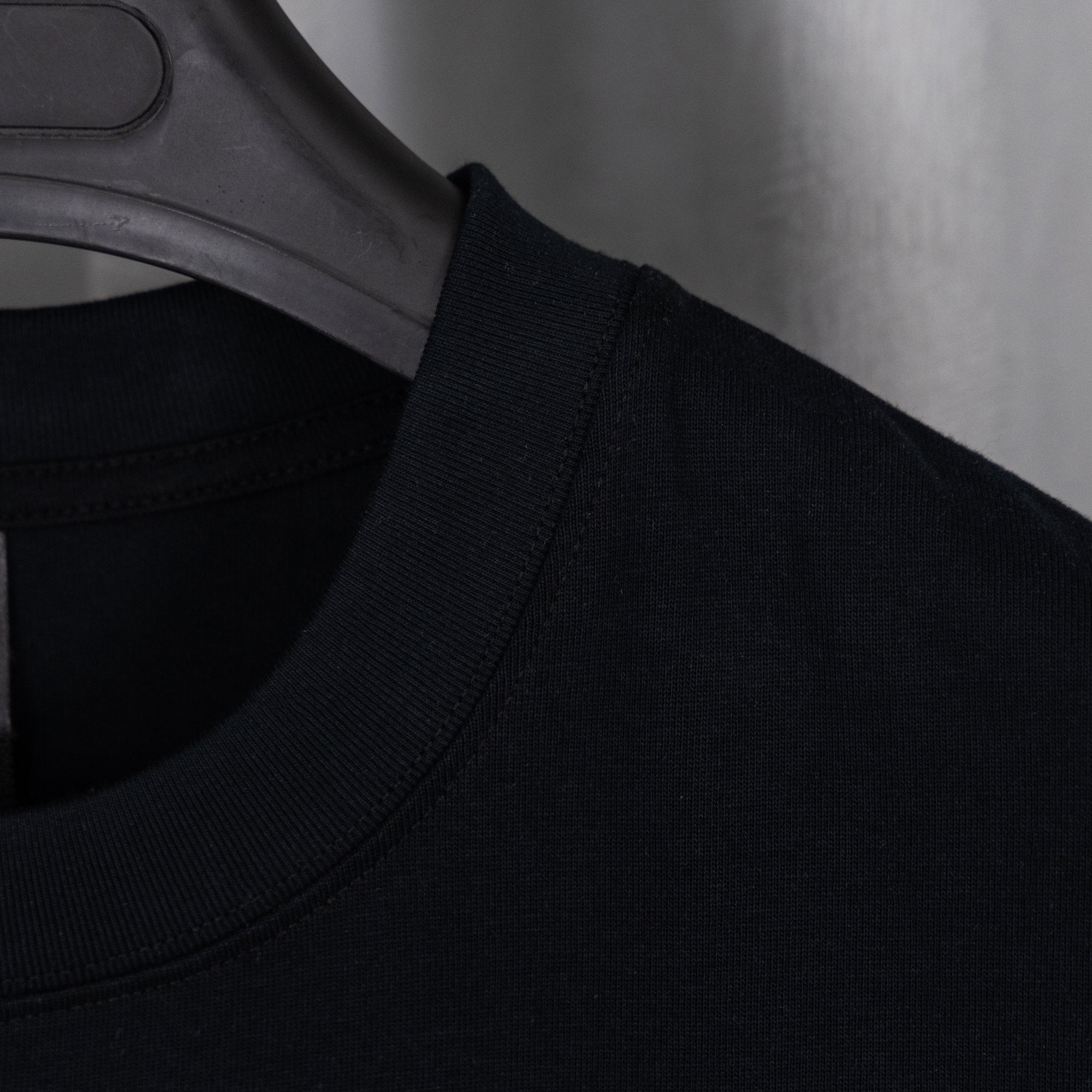 Black crew-neck T-shirt with ribbed collar on a hanger