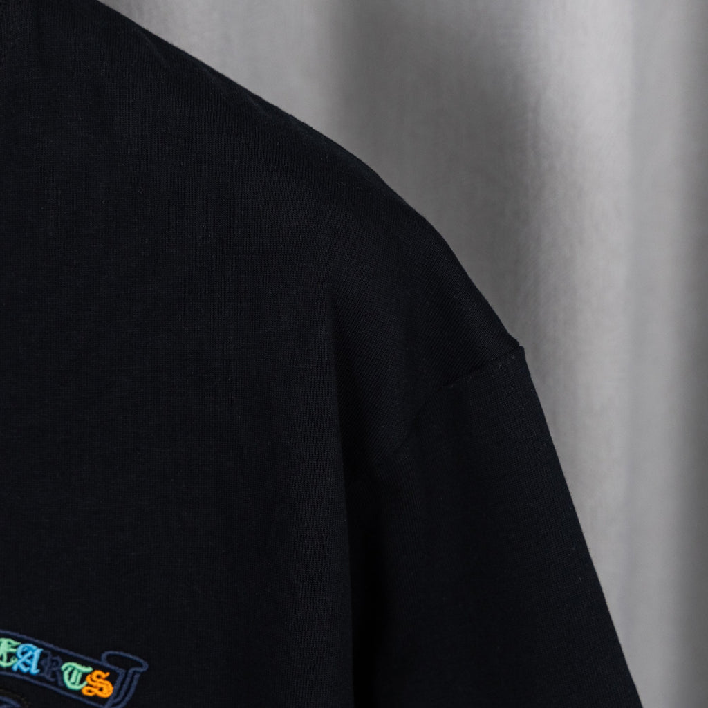 Black T-shirt sleeve with partial blue embroidered logo