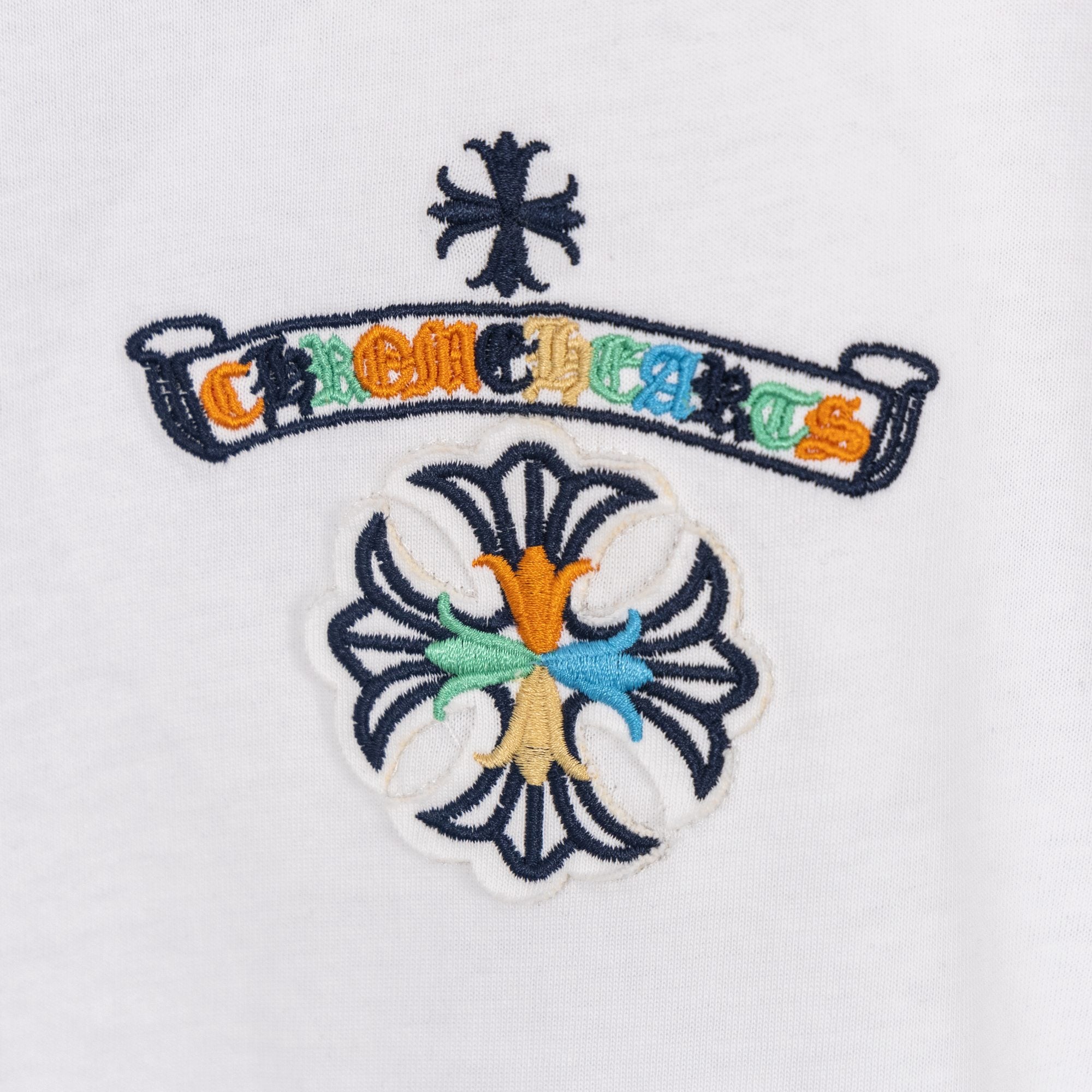 White T-shirt embroidered crown and flower crest graphic on the chest