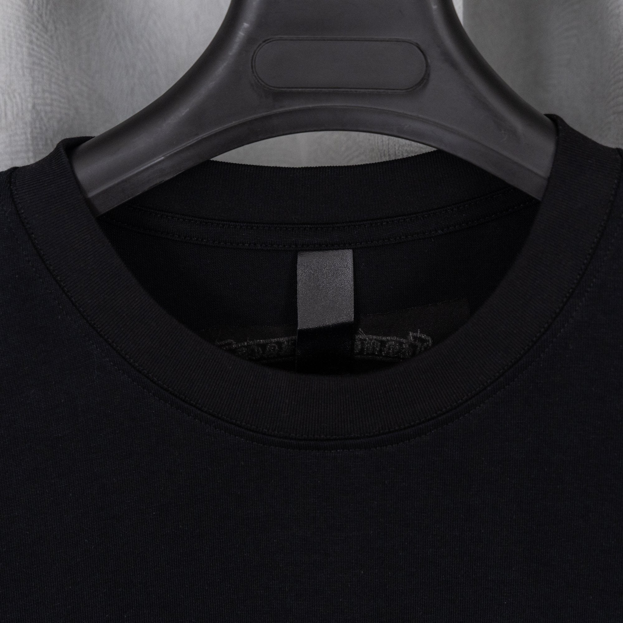 Black T-shirt collar and inner neck label view under hanger
