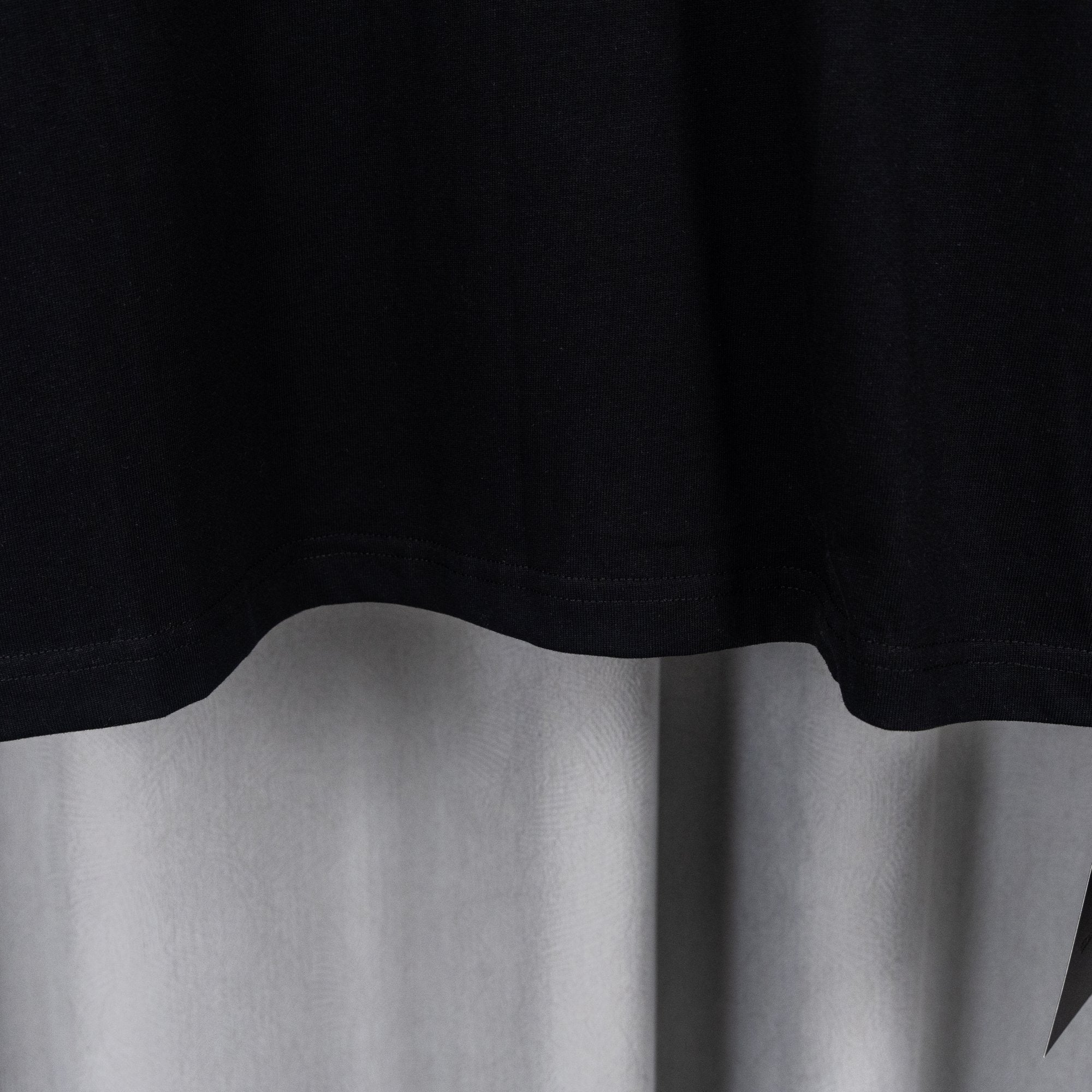 Black T-shirt lower hem with slight drape and clean stitched edge