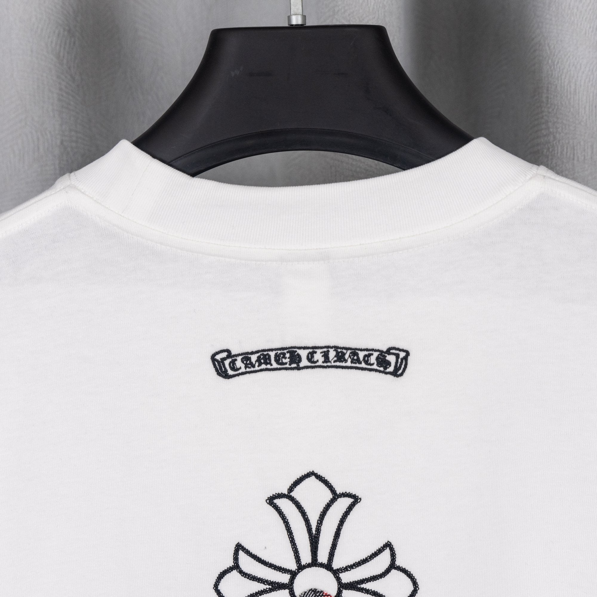 White crew-neck T-shirt collar with small back logo label and black outline graphic