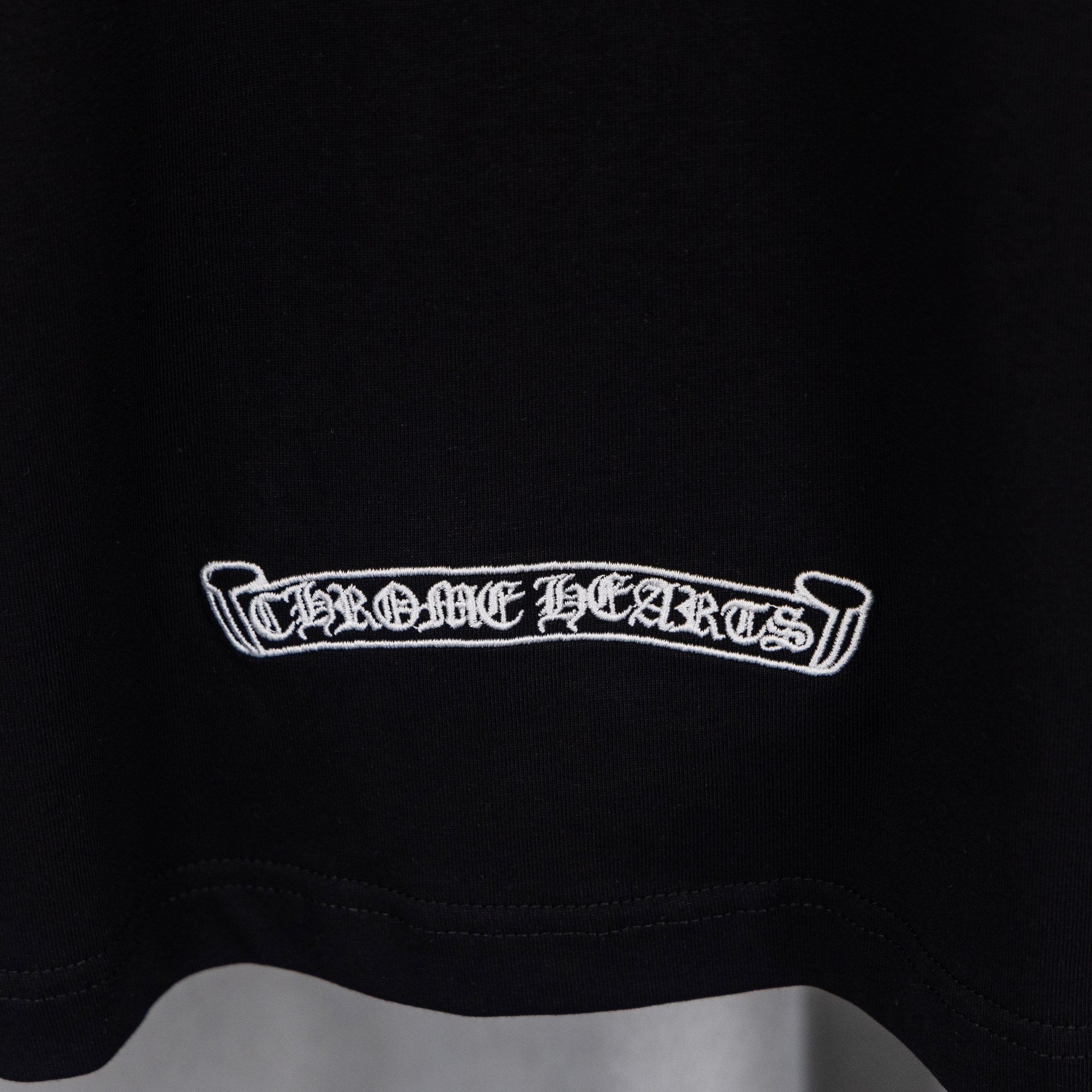 Black T-shirt with white rectangular text logo at lower chest.