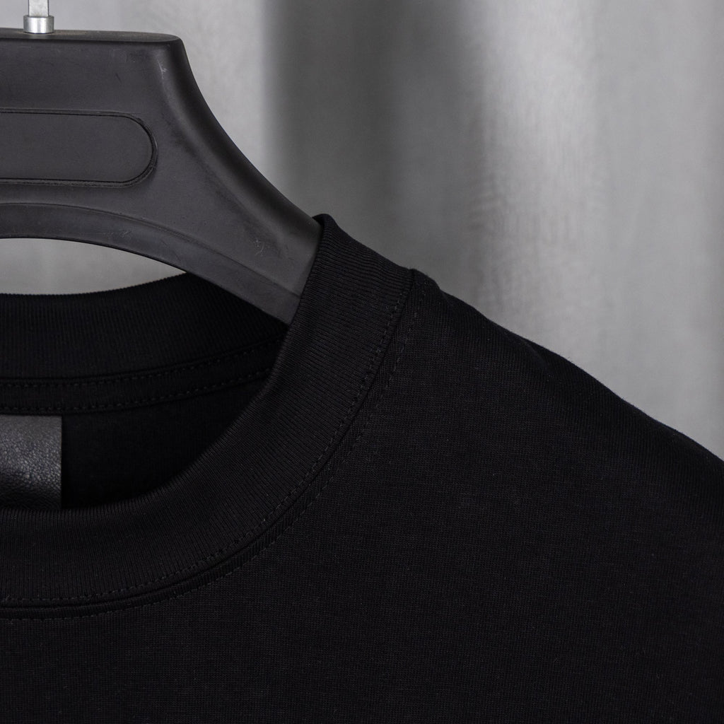 Black T-shirt neckline with black label at collar seam.