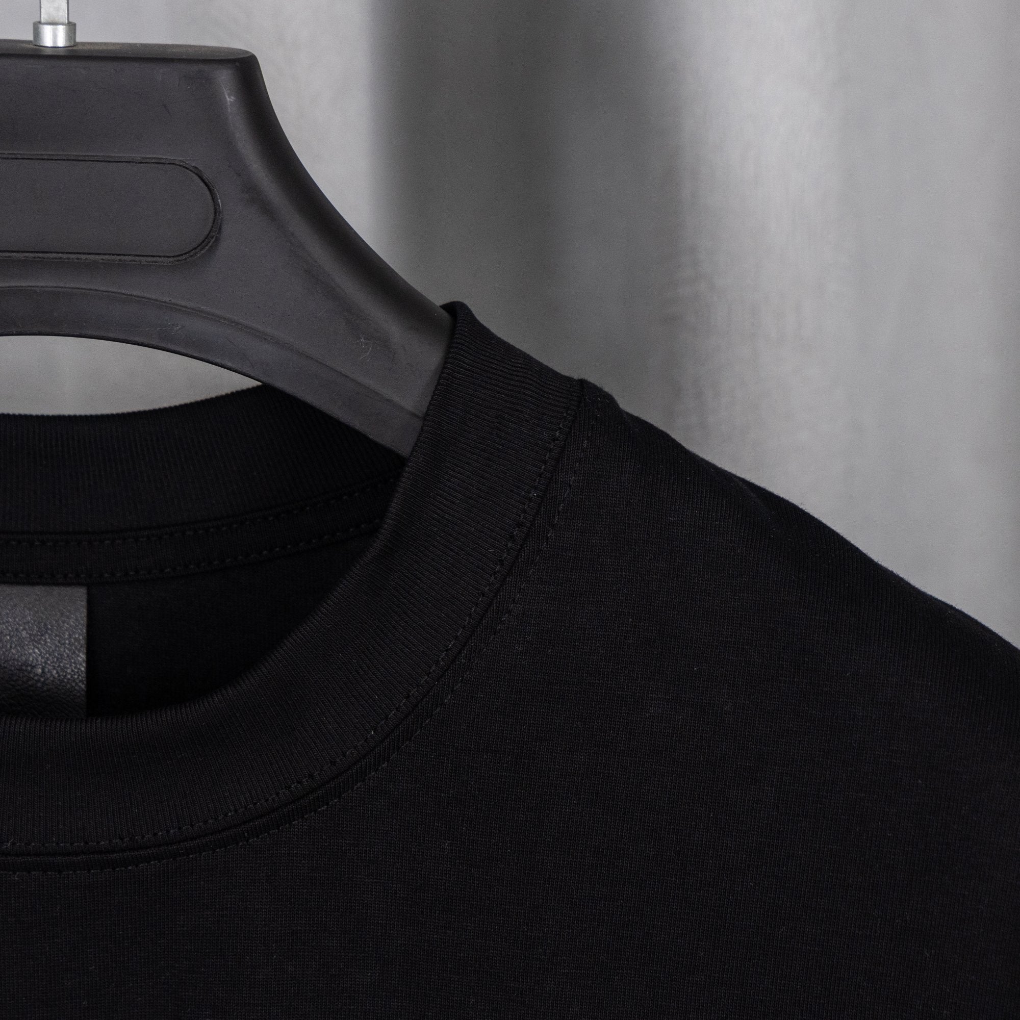 Black T-shirt neckline with black label at collar seam.