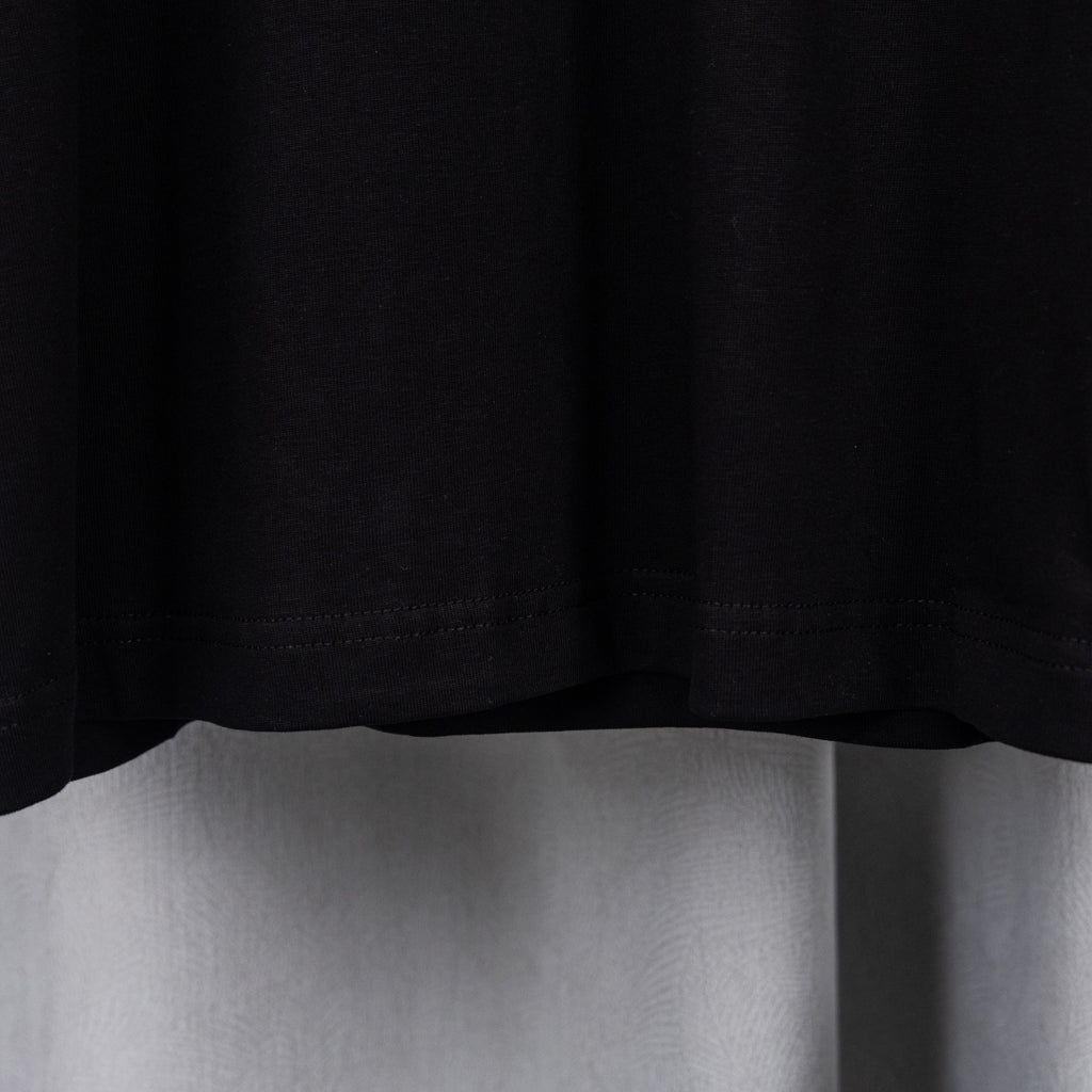 Black T-shirt bottom hem with visible stitching.