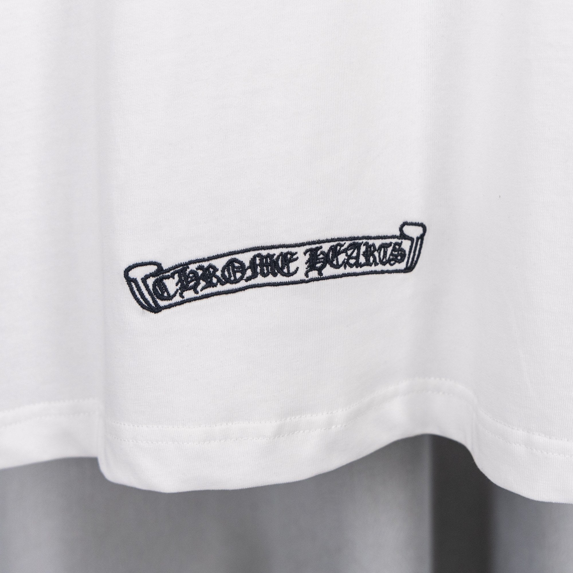White T-shirt with small ribbon-style graphic at lower chest