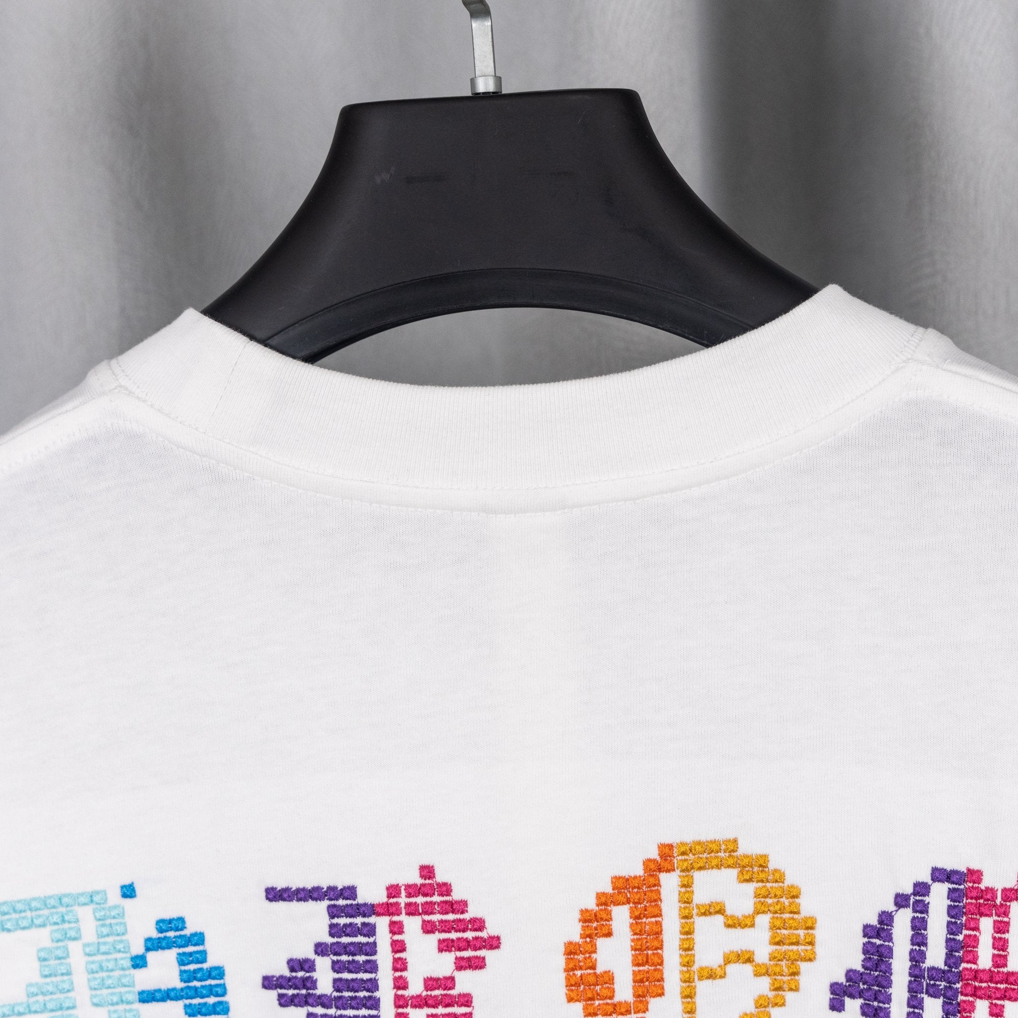 White crewneck T-shirt back view with colorful pixel-style graphic near hem