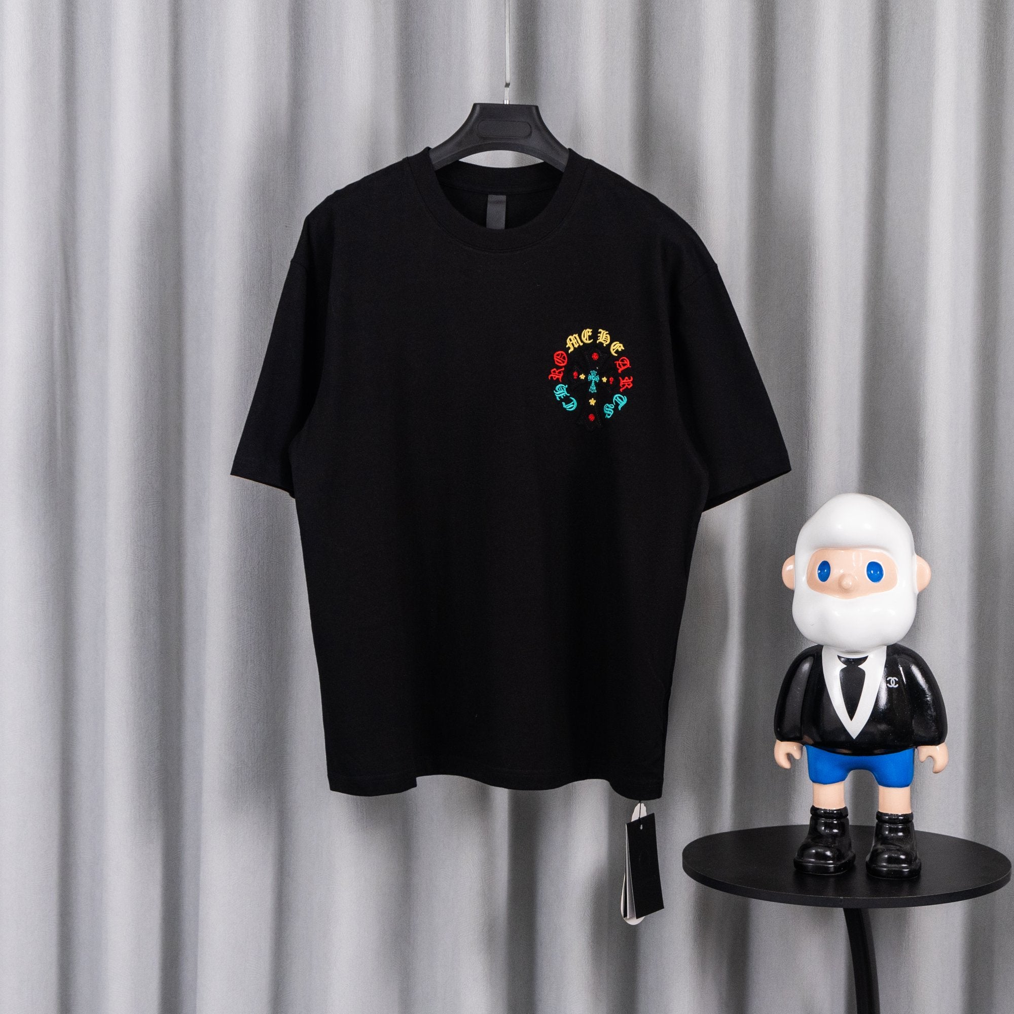Black short-sleeve T-shirt with small colorful circular cross graphic on chest