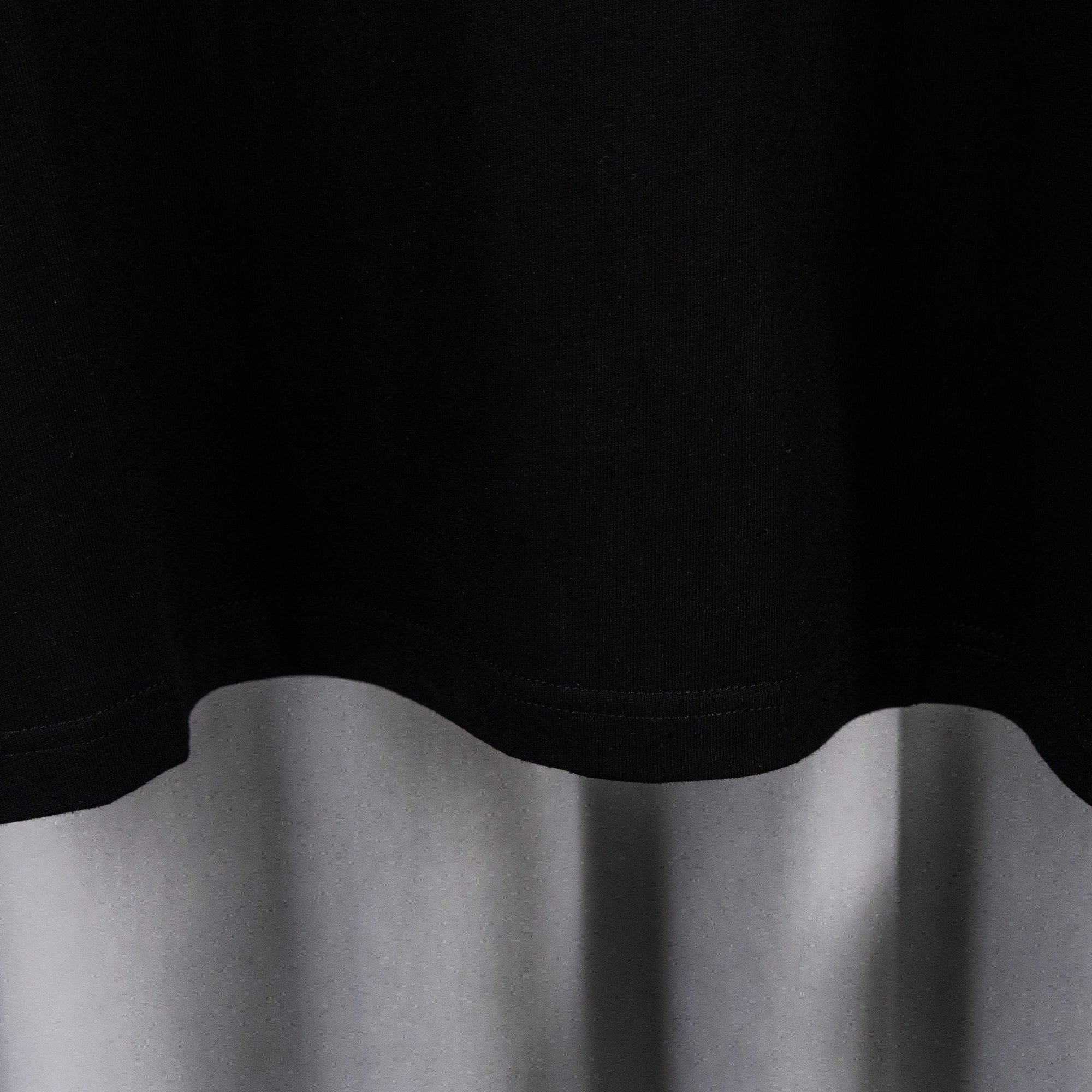 Black T-shirt lower hem with rounded cut and stitched edge